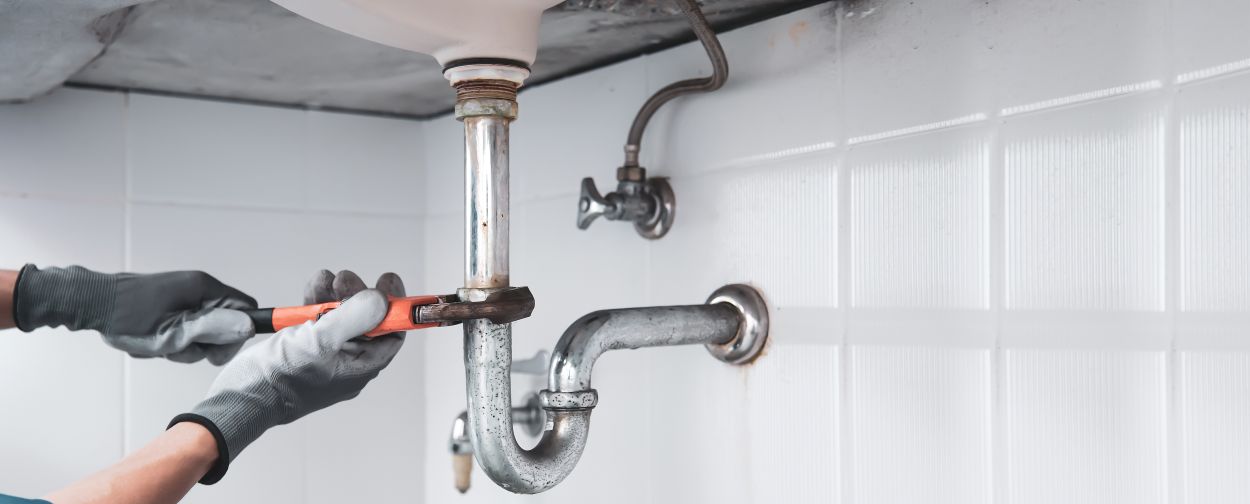 Technician plumber using a wrench to repair a water pipe under the sink. Concept of maintenance, fix water plumbing leaks, replace the kitchen sink drain, cleaning clogged pipes is dirty or ... See More